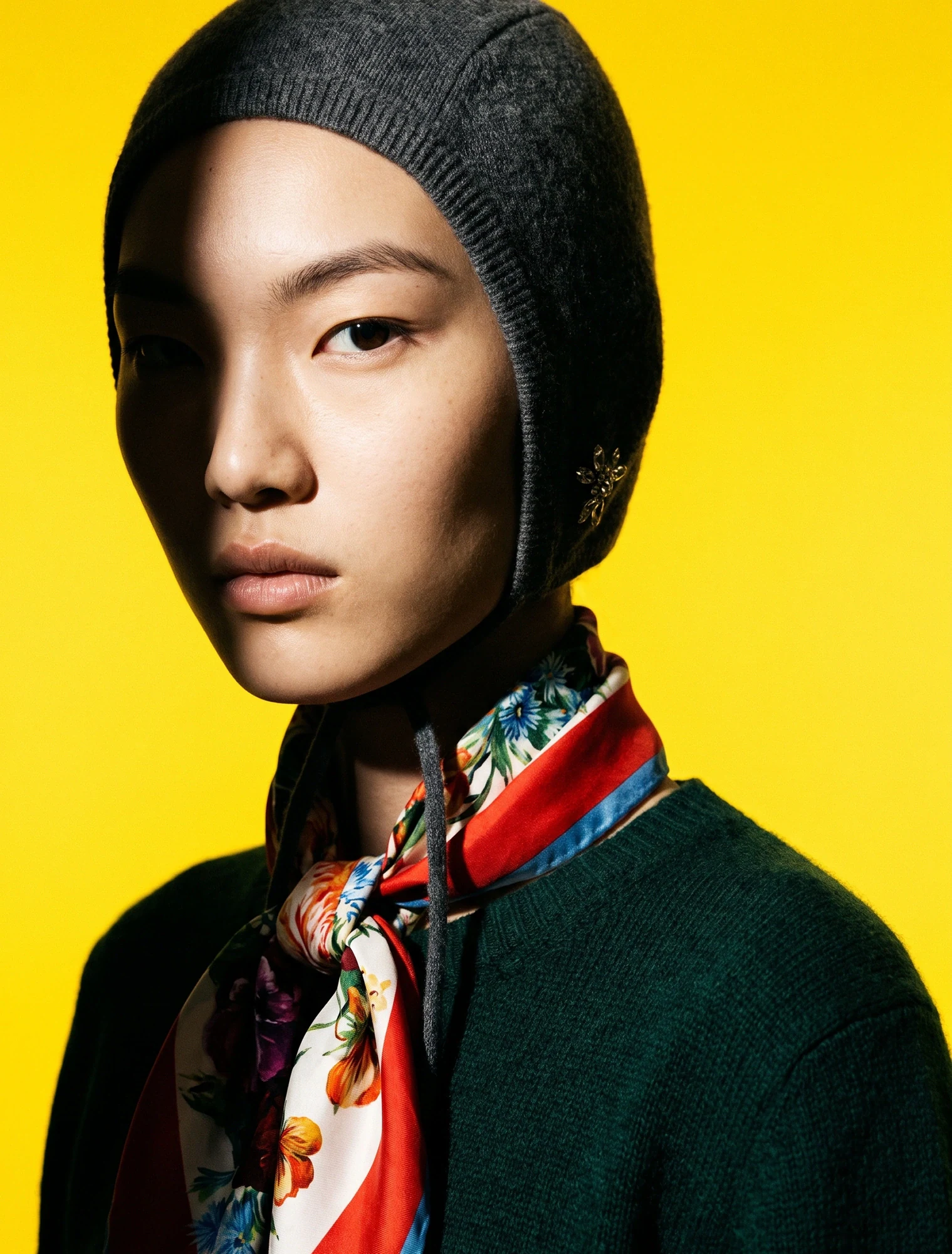 AI-generated on-model image: printed silk scarf and knit beanie against a yellow backdrop
