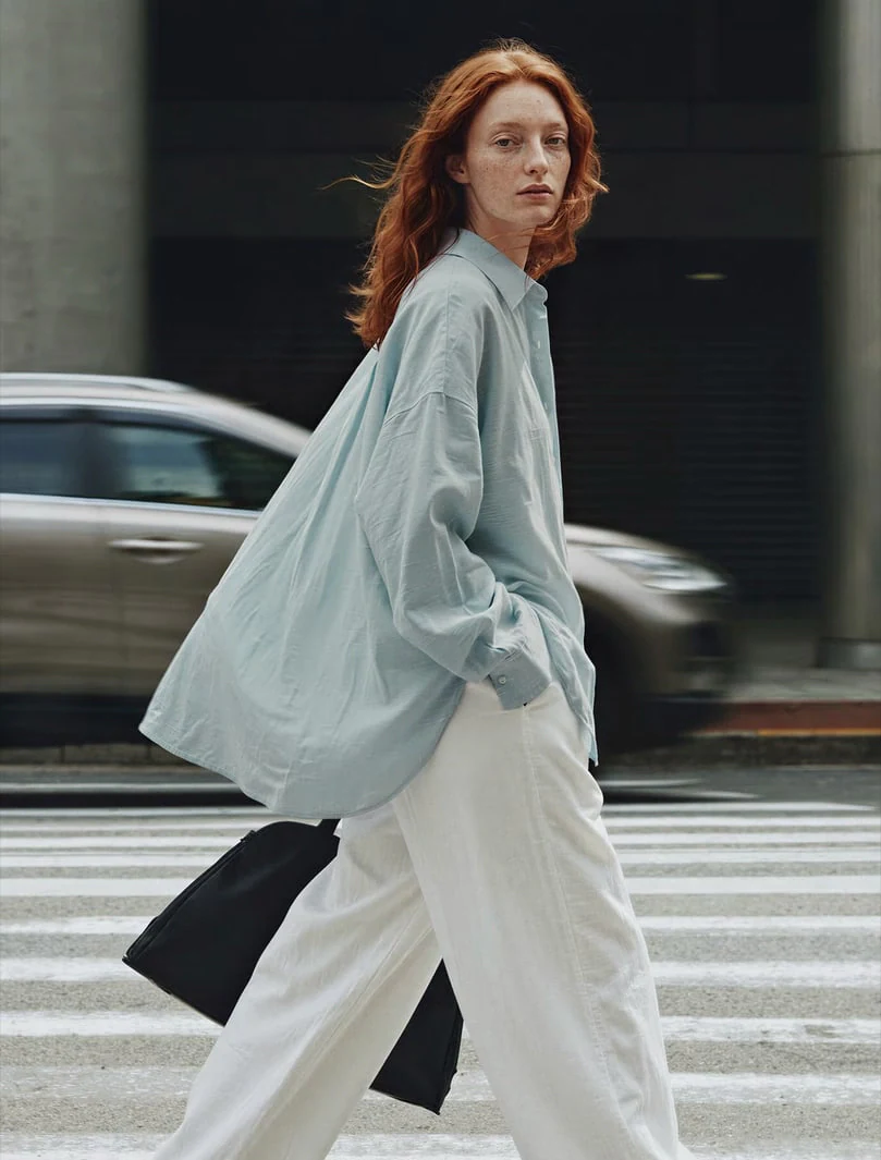 AI-generated on-model image: oversized shirt and wide trousers shot in motion on a crossing