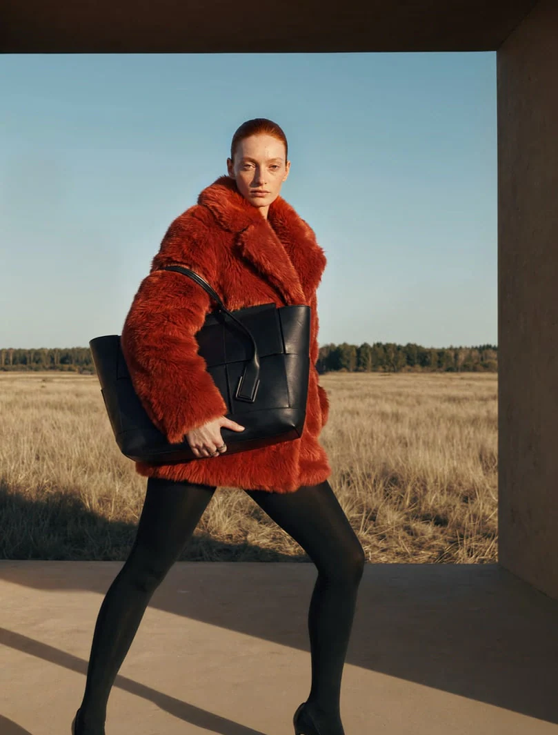 AI-generated on-model image: red shearling coat photographed against a field