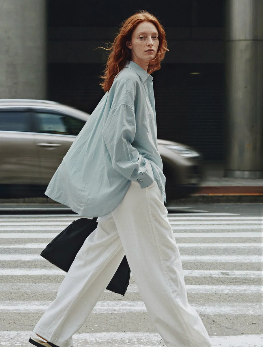 AI-generated on-model image: oversized shirt and wide trousers on a city crossing