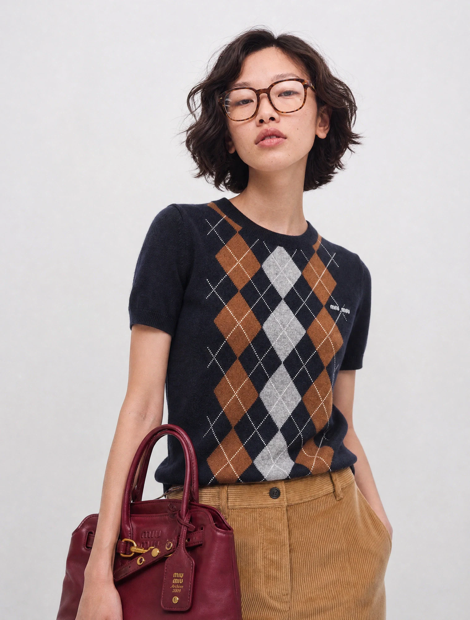 AI-generated on-model image: argyle knit top with corduroy trousers and a bag