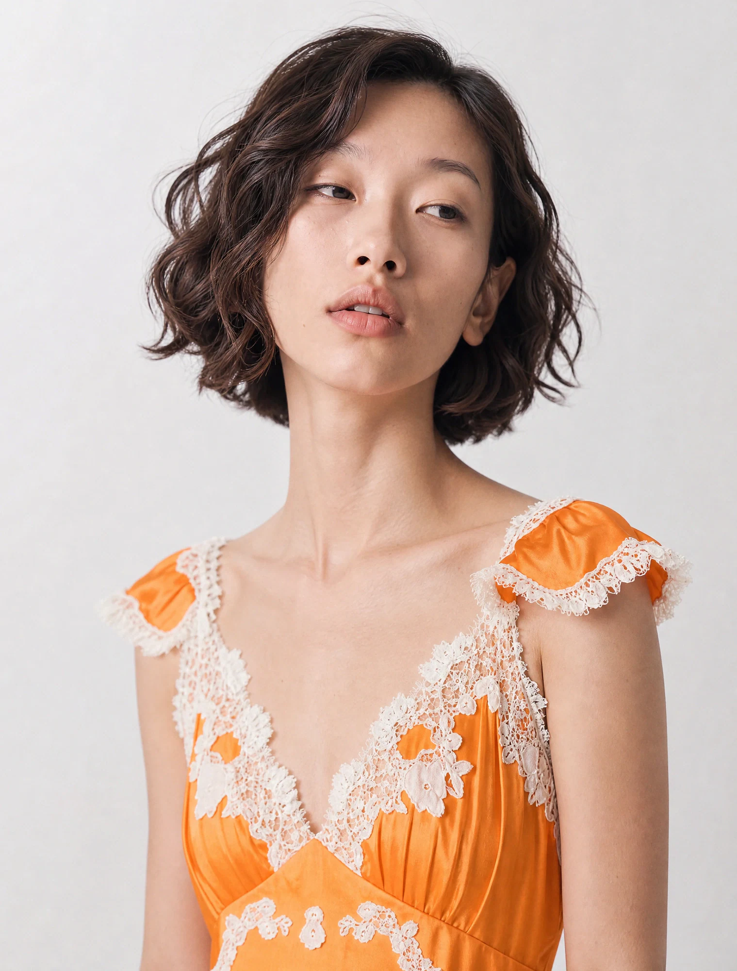 AI-generated on-model image: orange lace-trim slip dress, close-up portrait