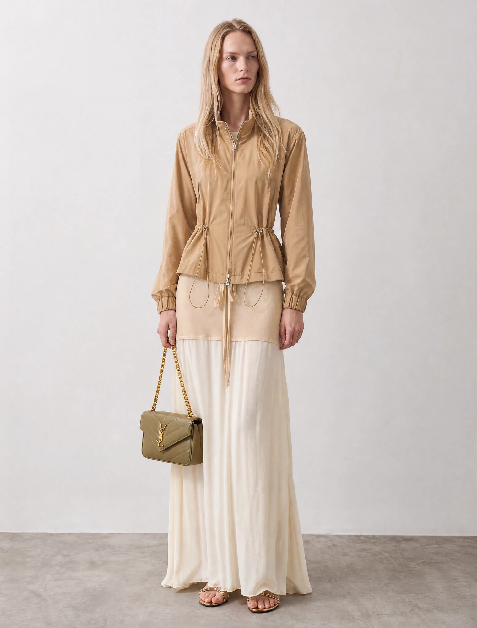 AI-generated on-model image: beige high-neck jacket over a pleated maxi skirt